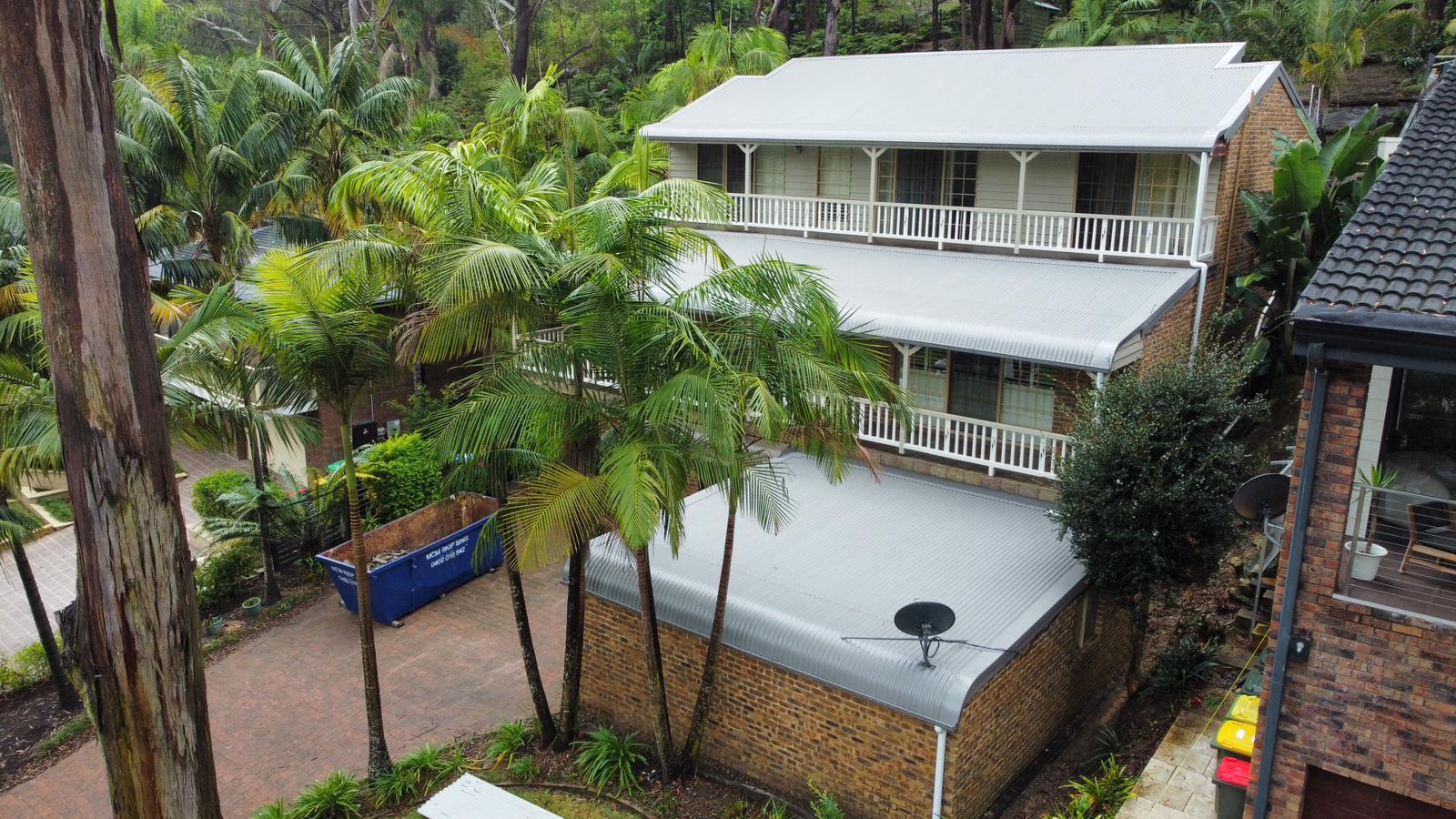 Two-story house with palm trees.