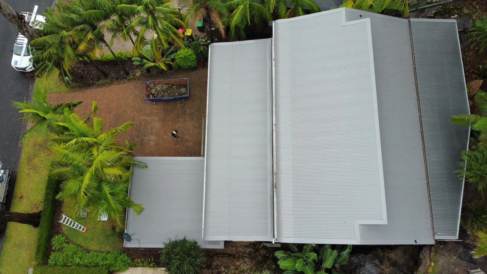 Aerial view of house with metal roof and palm trees.