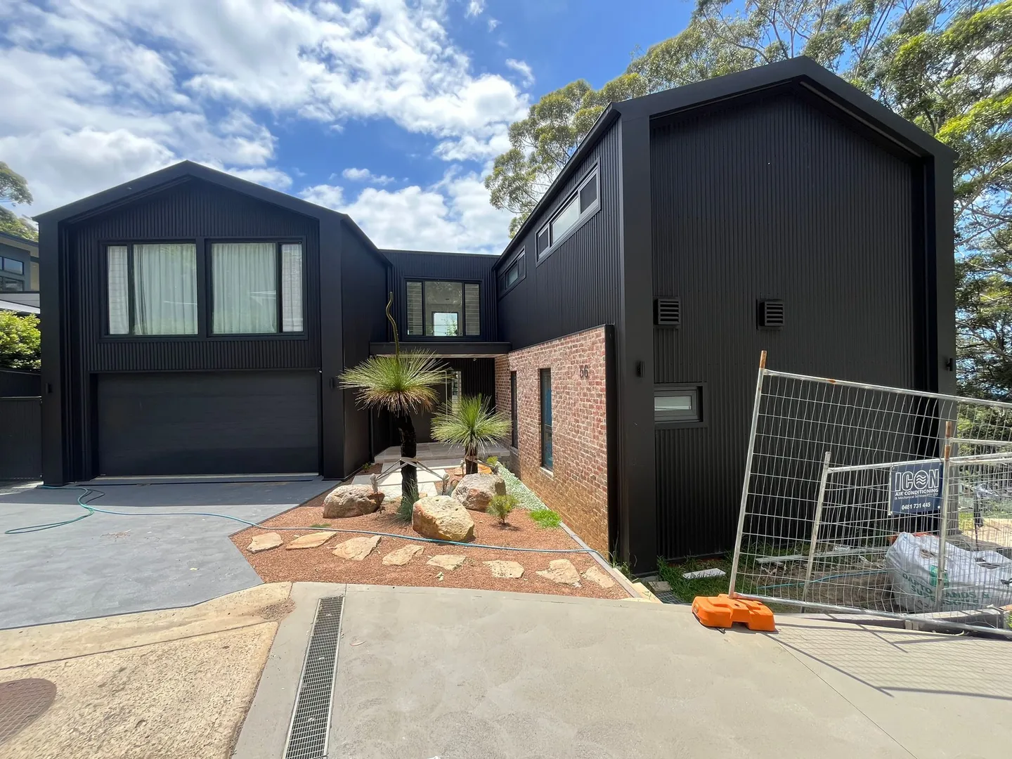Modern black house with garage and garden.