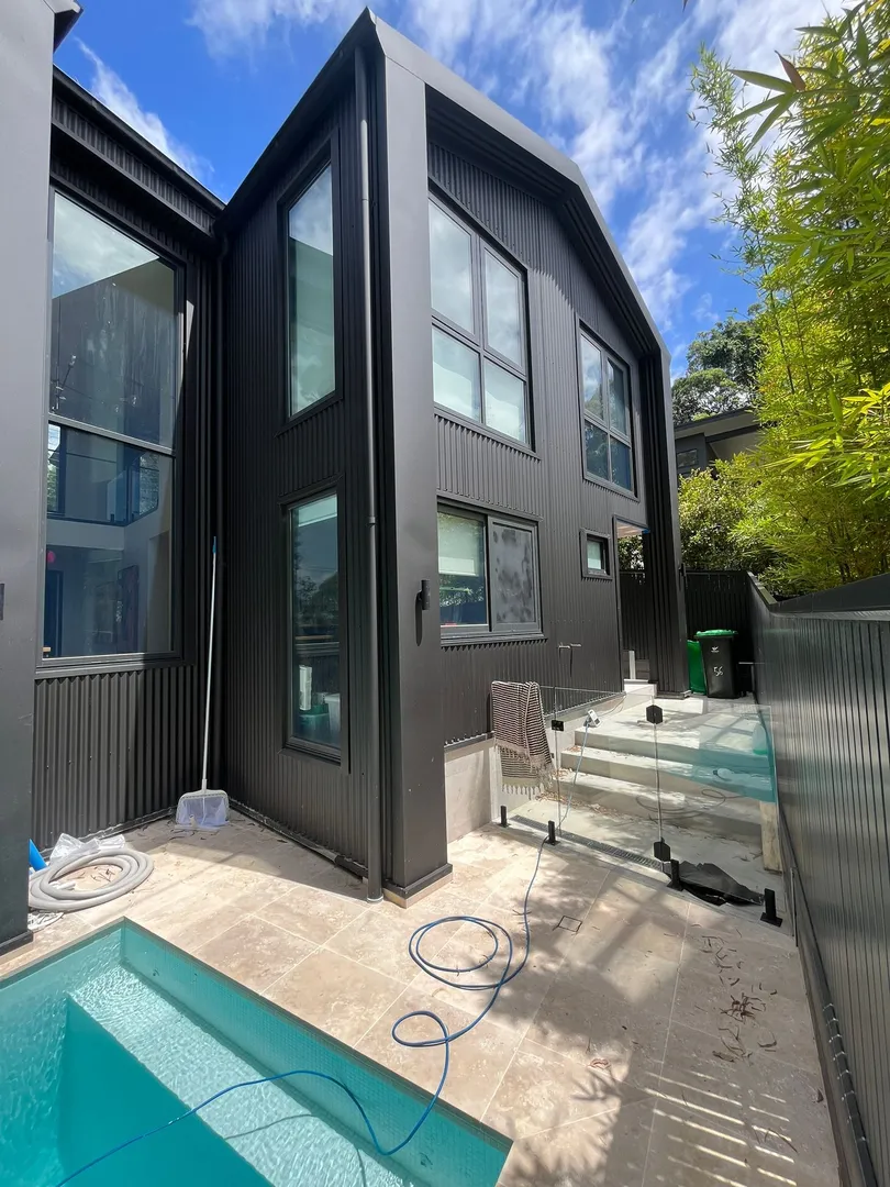 Modern black house with pool under blue sky.