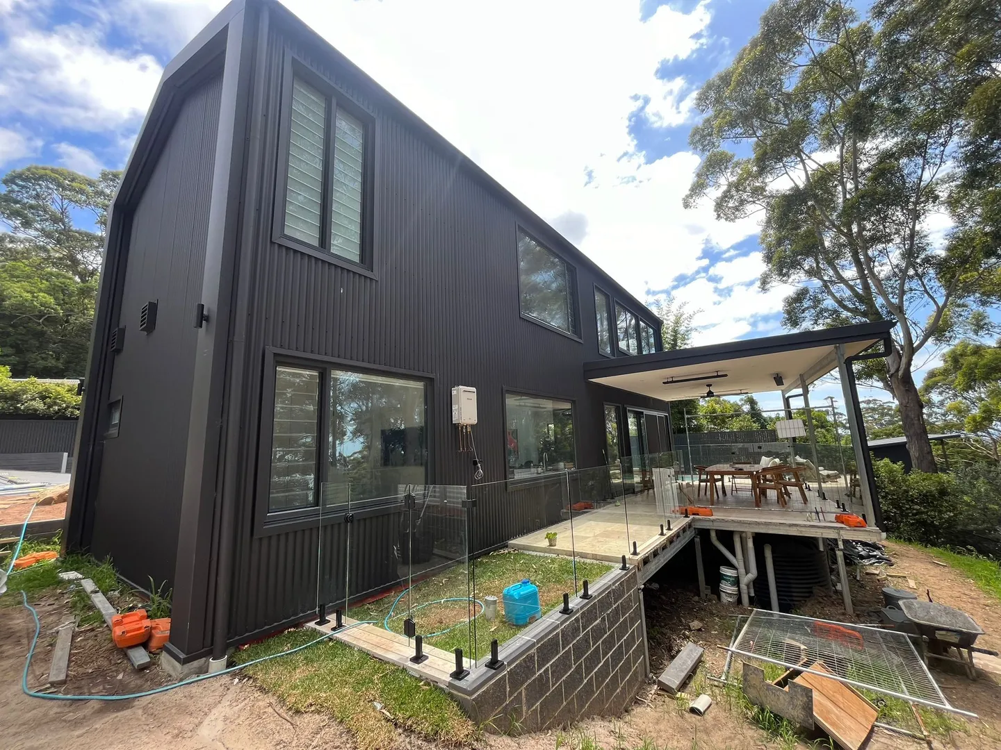 Modern black house with outdoor patio and trees.