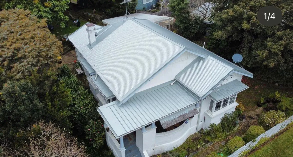 Aerial view of a white house with metal roof